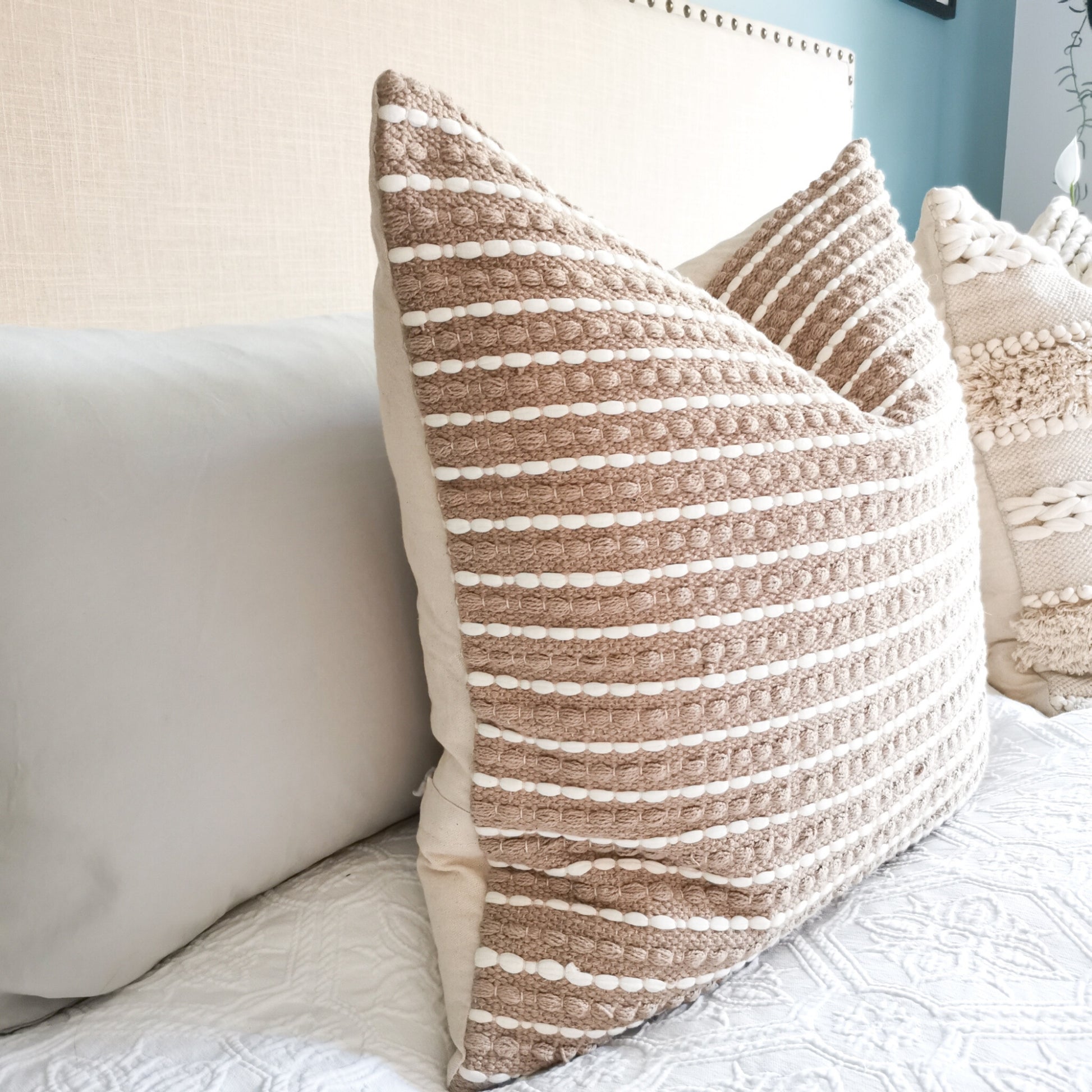 Hand loom woven pillows on a white bed