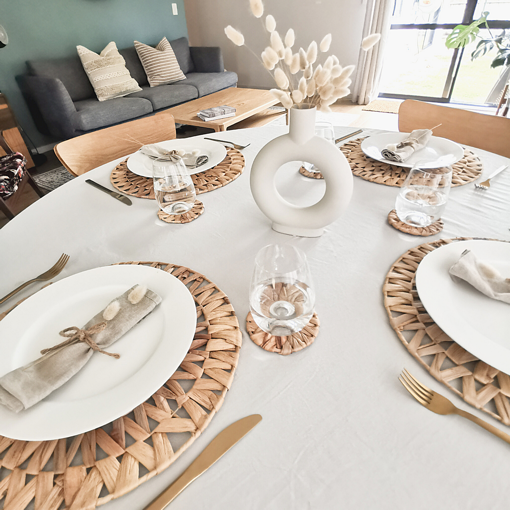 Woven placemats styled to create a boho dining table with pampas grass, nordic vase, and gold utensils