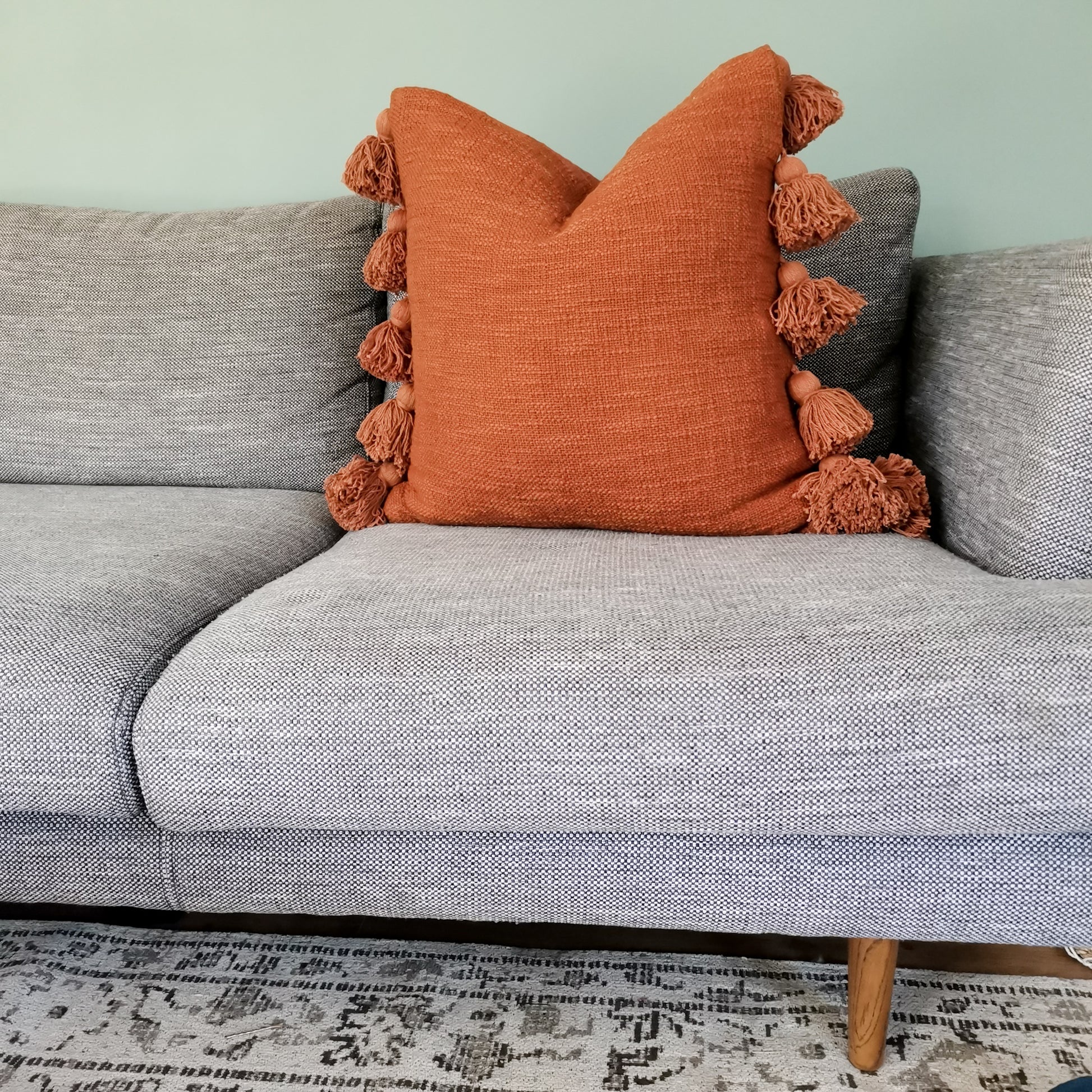 Rust throw pillow with tassels for family living room